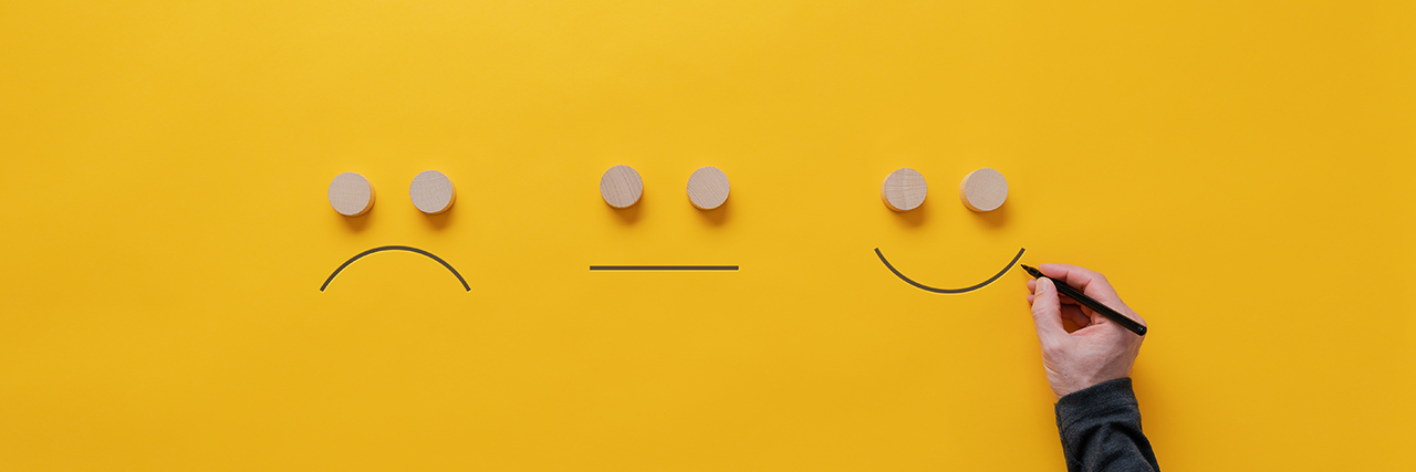 Customer feedback and satisfaction conceptual image - male hand drawing happy, sad and neutral faces over a yellow background.