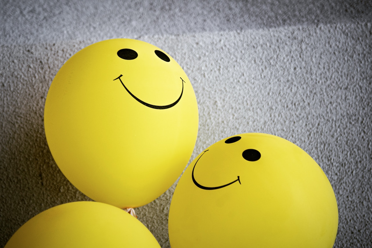 Three yellow smiley face balloons